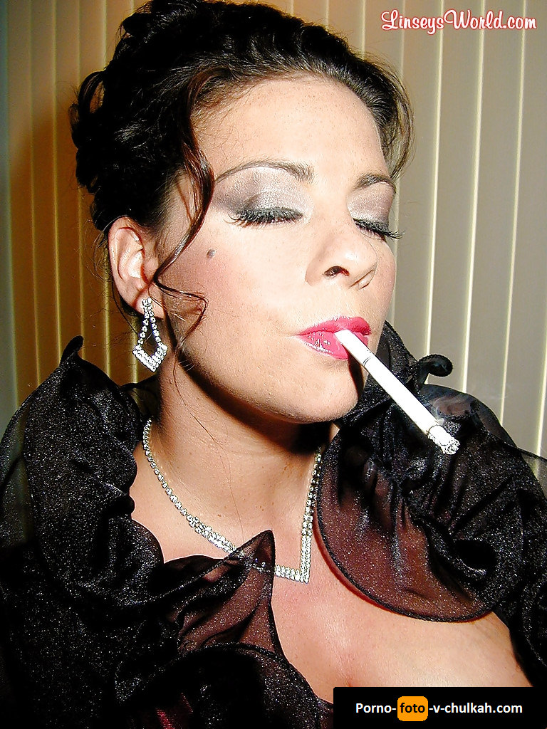 Сочная грудастая мадам в эротичном прикиде ласкает пизду под трусиками, покуривая сигарету